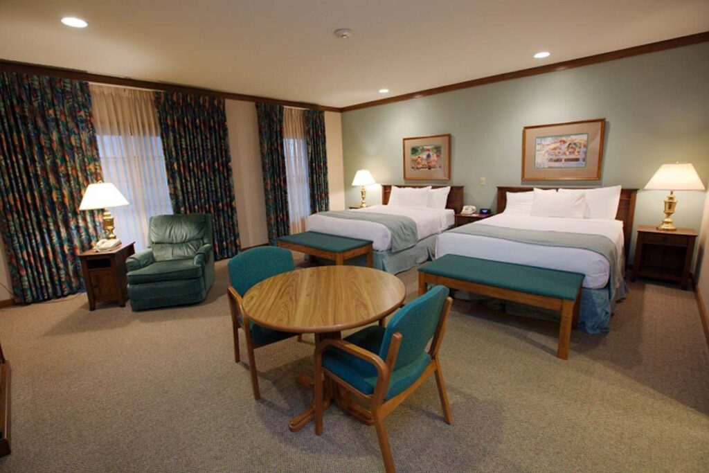 Hotel room with two beds, an armchair, and a table with two chairs